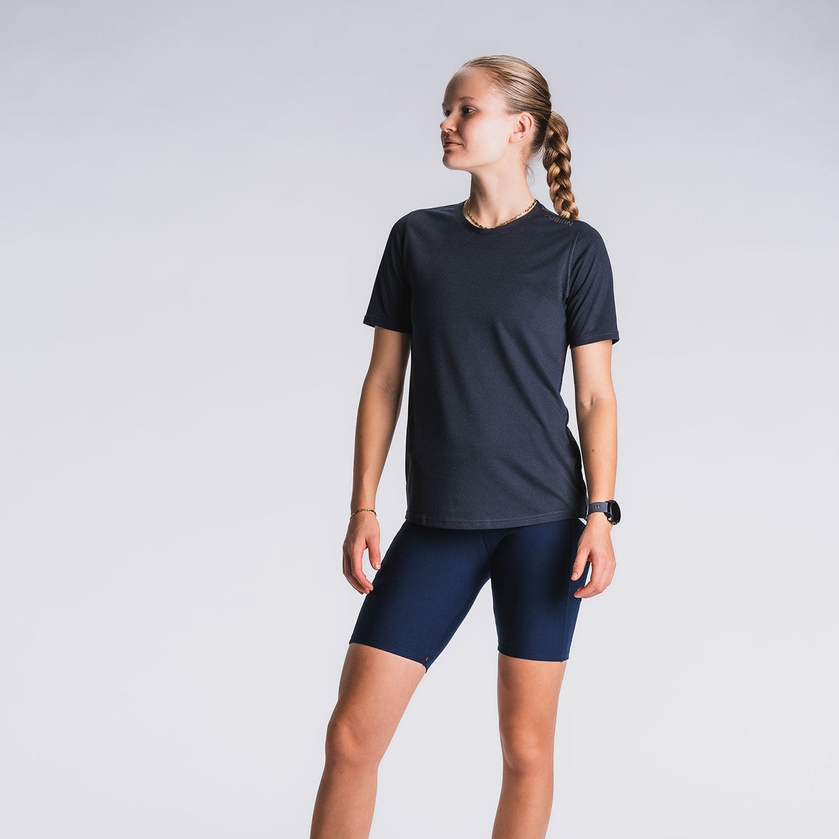 Vrouw in zwart T-shirt en donkerblauwe hardloopshorts, witte achtergrond