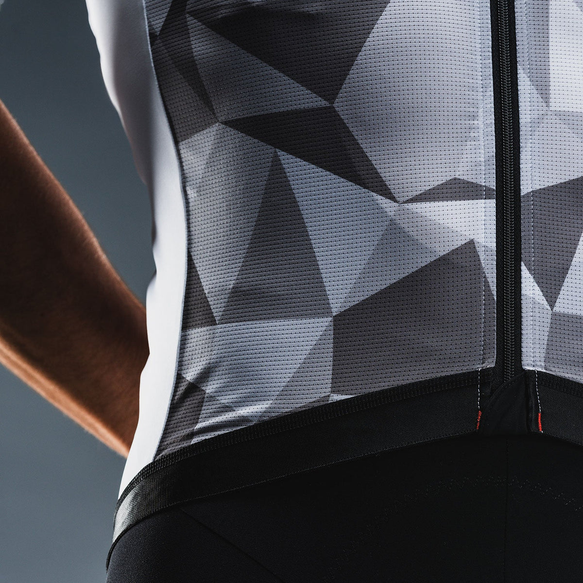 Close‑up van zwart‑grijs fietsshirt met geometrisch patroon en ademend materiaal met kleine perforaties