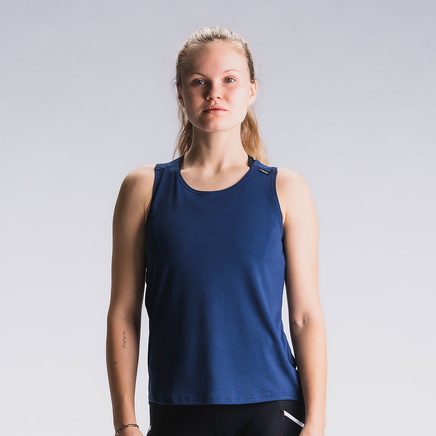 Vrouw in blauw hardlooptop, vooraanzicht, lichtgrijze achtergrond