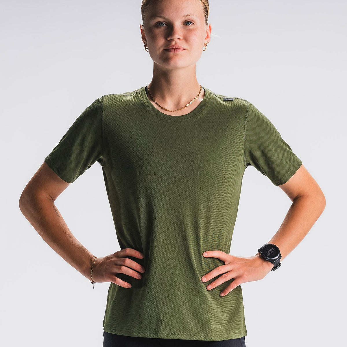 Vrouw in groen sport-T-shirt, lichtgrijze achtergrond