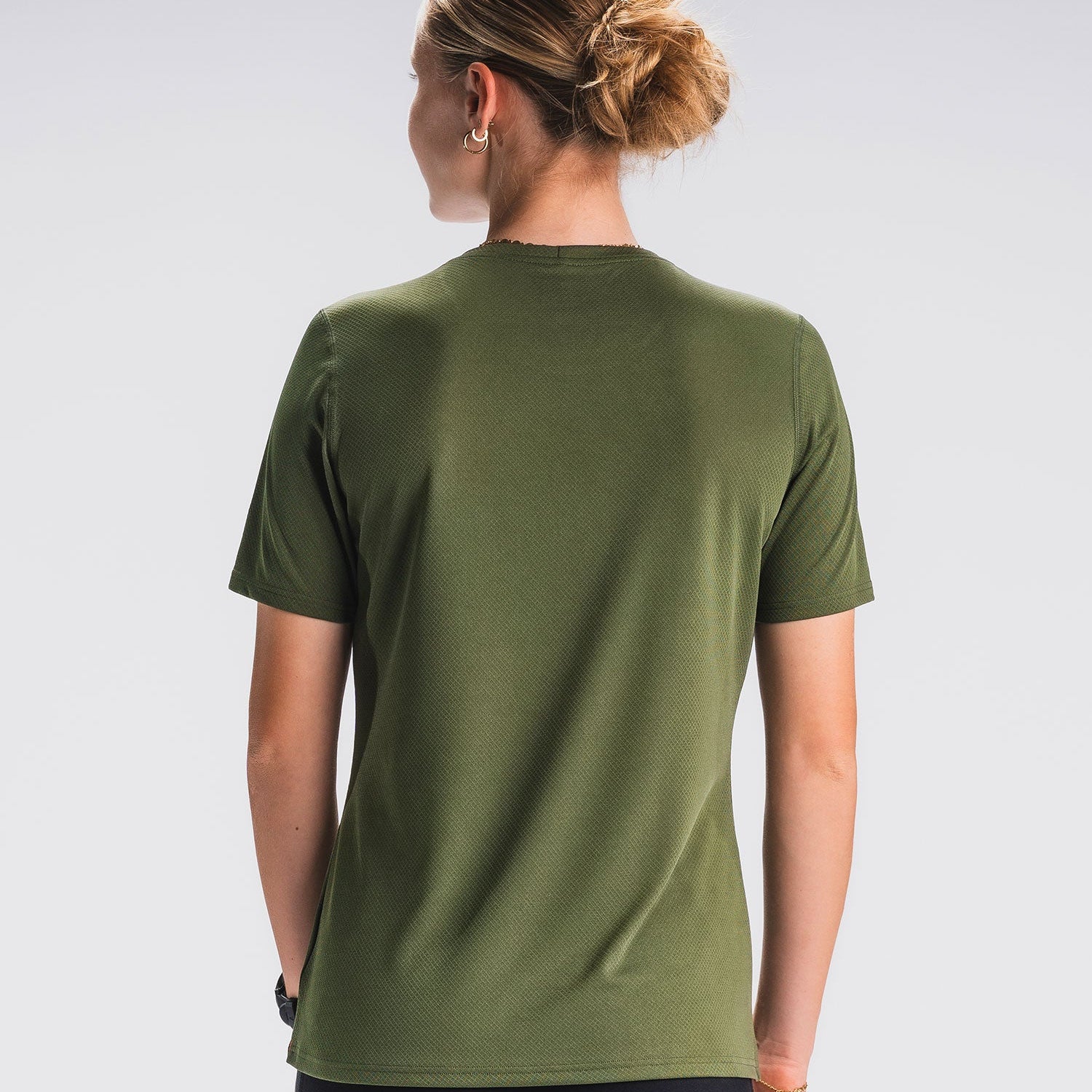 Vrouw in groen hardloop-T-shirt, achteraanzicht, witte achtergrond