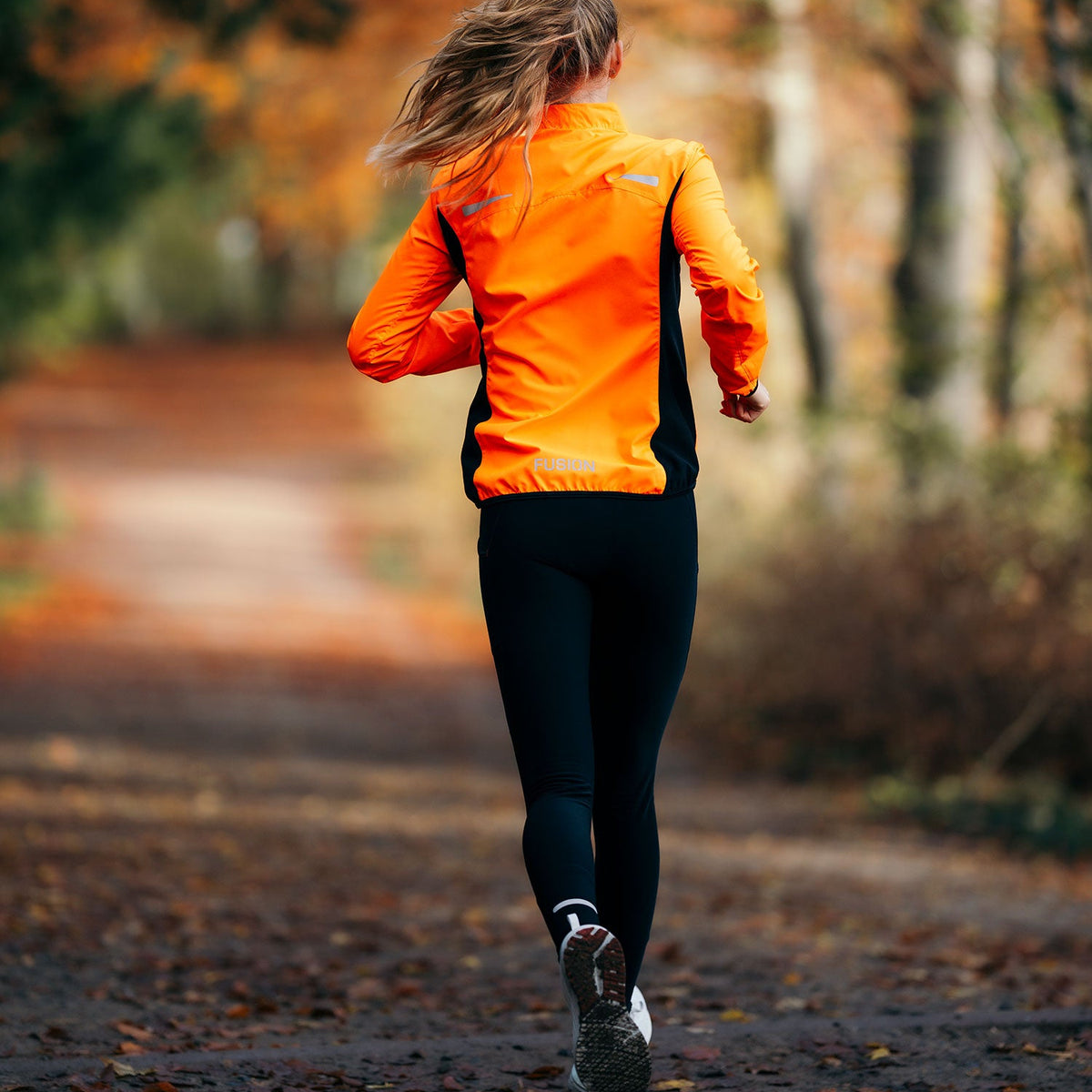 Achteraanzicht van vrouw die hardloopt op een pad in een herfstbos