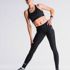 Vrouw in zwart sportoutfit, lichtgrijze achtergrond