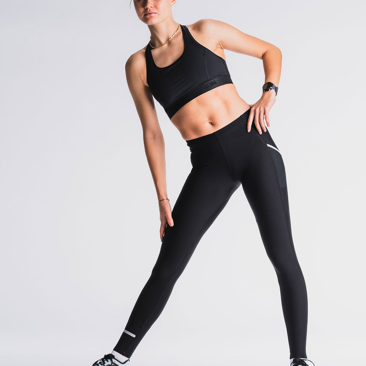 Vrouw in zwart sportoutfit, lichtgrijze achtergrond