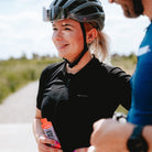 Vrouw met fietshelm die een Overstims Energix Gel vasthoudt