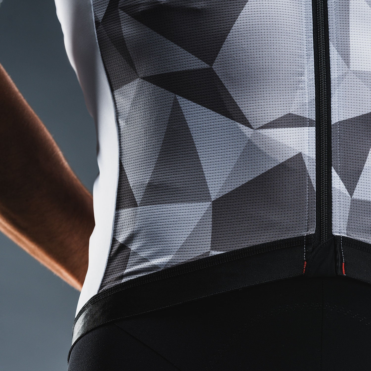 Close‑up van zwart‑grijs fietsshirt met geometrisch patroon en ademend materiaal met kleine perforaties