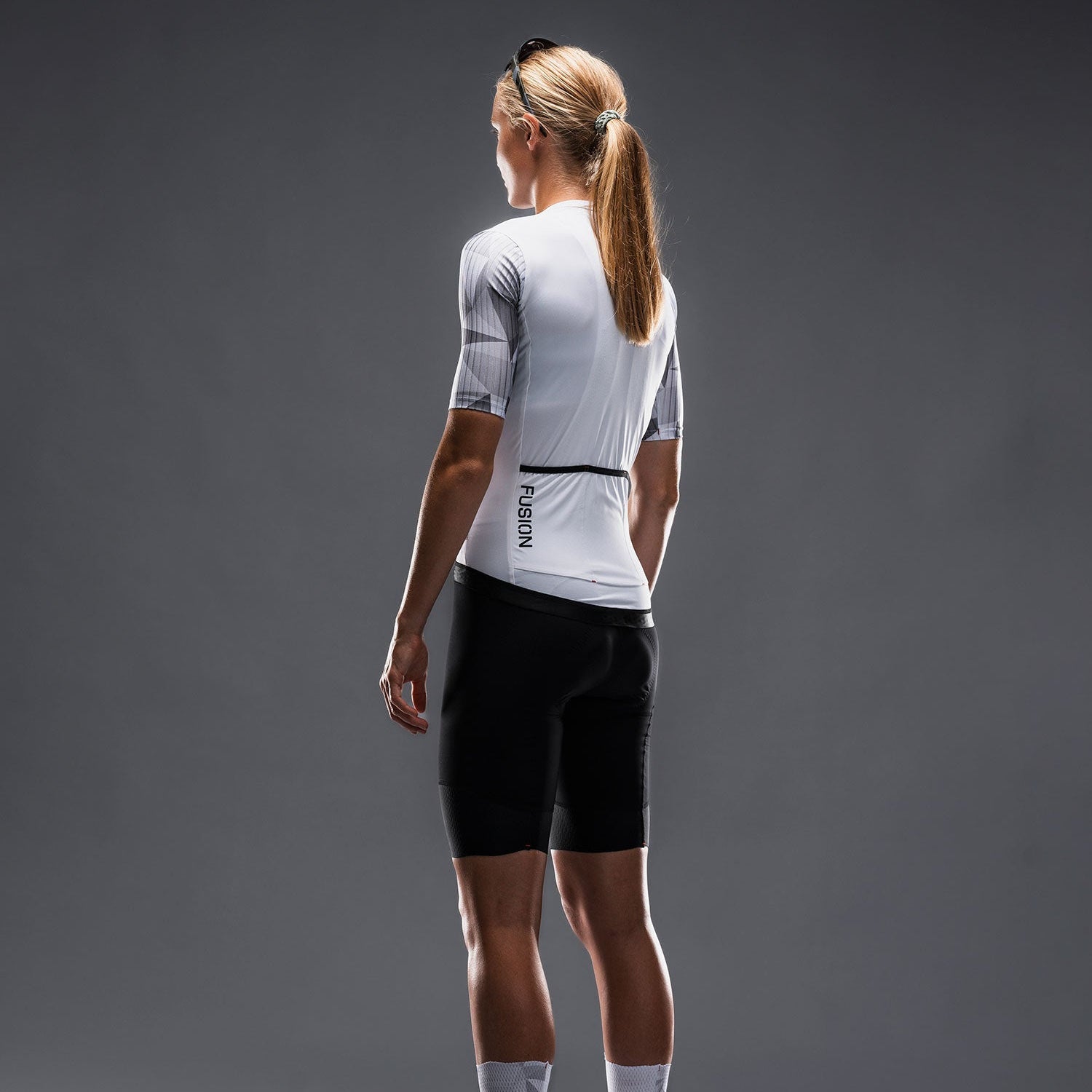 Achterkant van vrouw in Fusion fietsshirt en fietsbroek