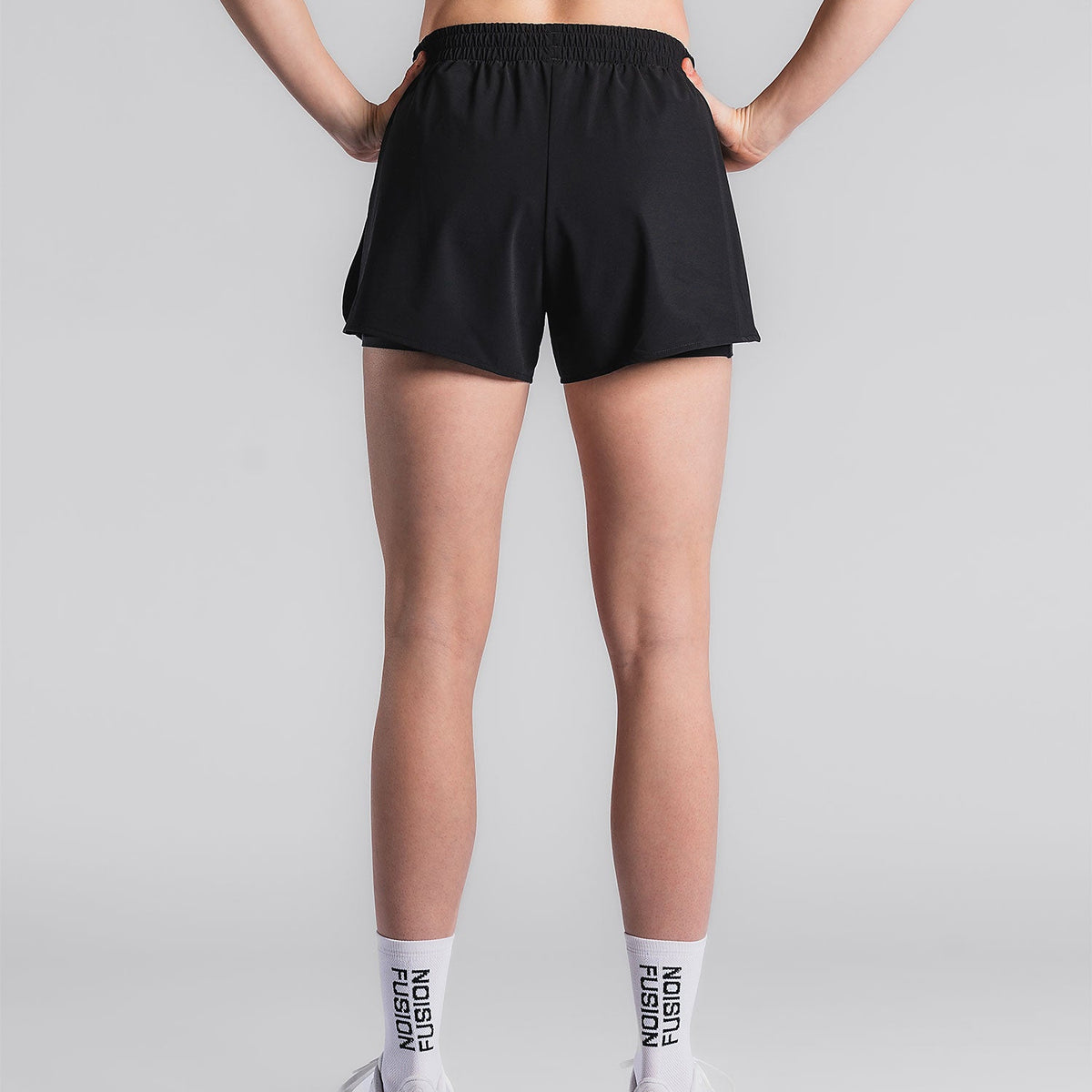 Achterkant van zwarte hardloopshort met witte Fusion‑sokken zichtbaar