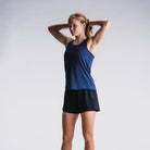 Vrouw in blauw hardlooptop en zwarte hardloopshorts, witte achtergrond