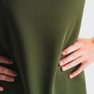 Close-up van vrouw in groen hardloop-T-shirt met ademend materiaal, handen op heupen, witte achtergrond